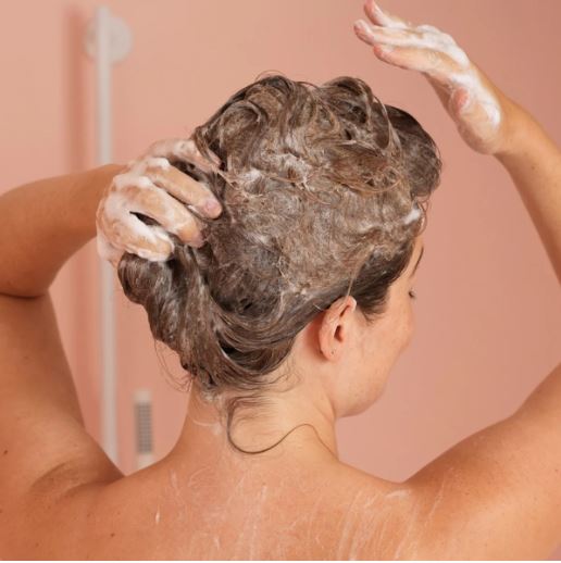 Mujer se lava el pelo con ReNu Smoothing Shampoo de Nu Skin
